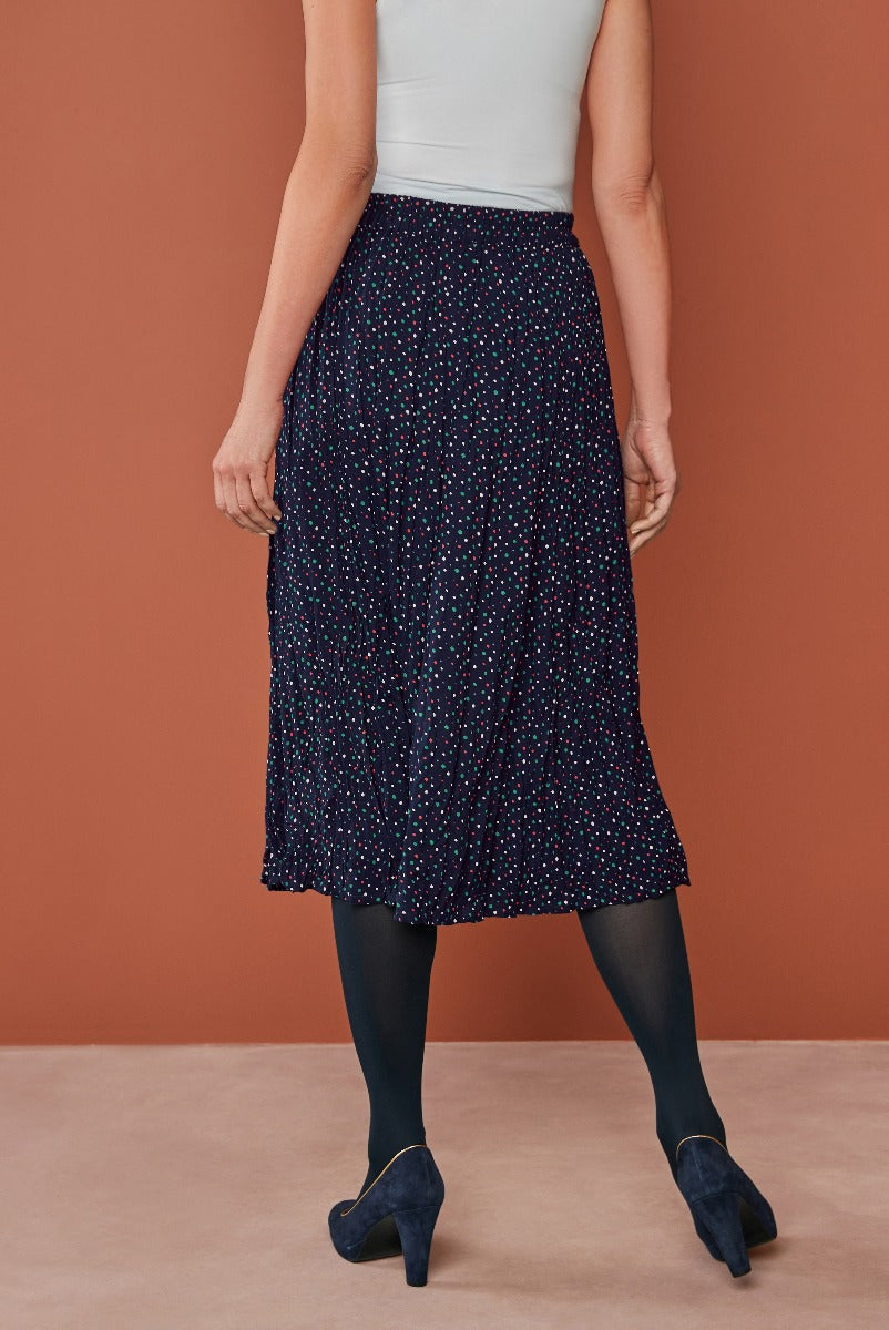 Lily Ella Collection navy blue polka dot midi skirt with elastic waistband, paired with opaque tights and blue suede heels, fashionable women's clothing.