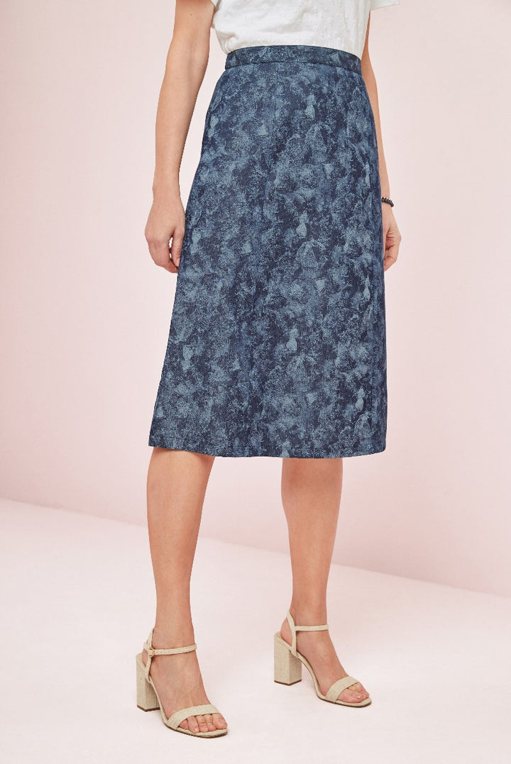 Lily Ella Collection elegant blue floral print midi skirt for women paired with beige strappy heels against a pink backdrop
