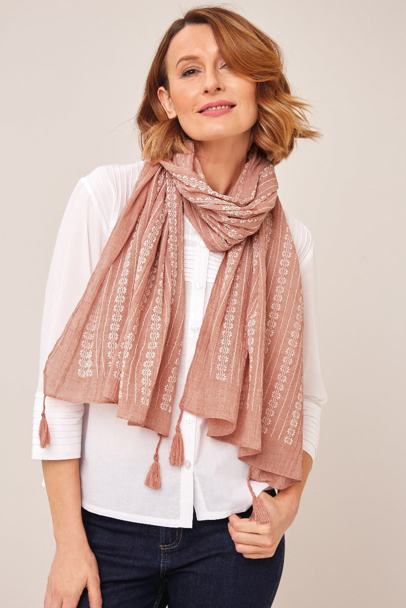 Lily Ella Collection elegant blush pink tasseled scarf with delicate white embroidery, styled with classic white shirt and denim for a smart-casual look.