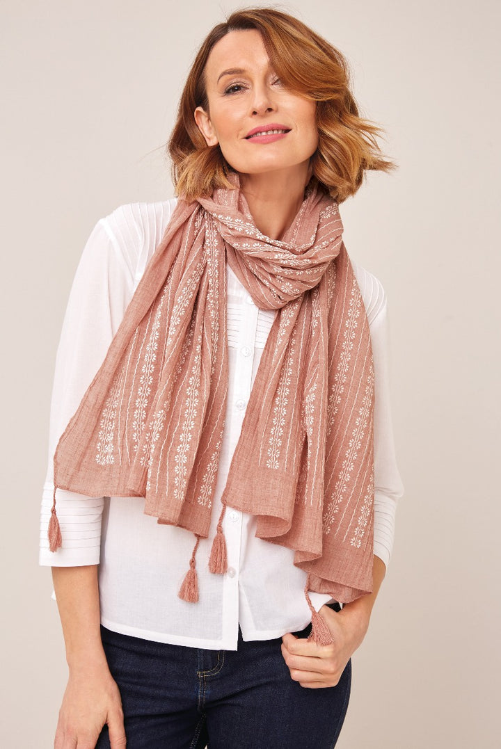 Lily Ella Collection elegant blush pink tasseled scarf with delicate white embroidery, styled with classic white shirt and denim for a smart-casual look.