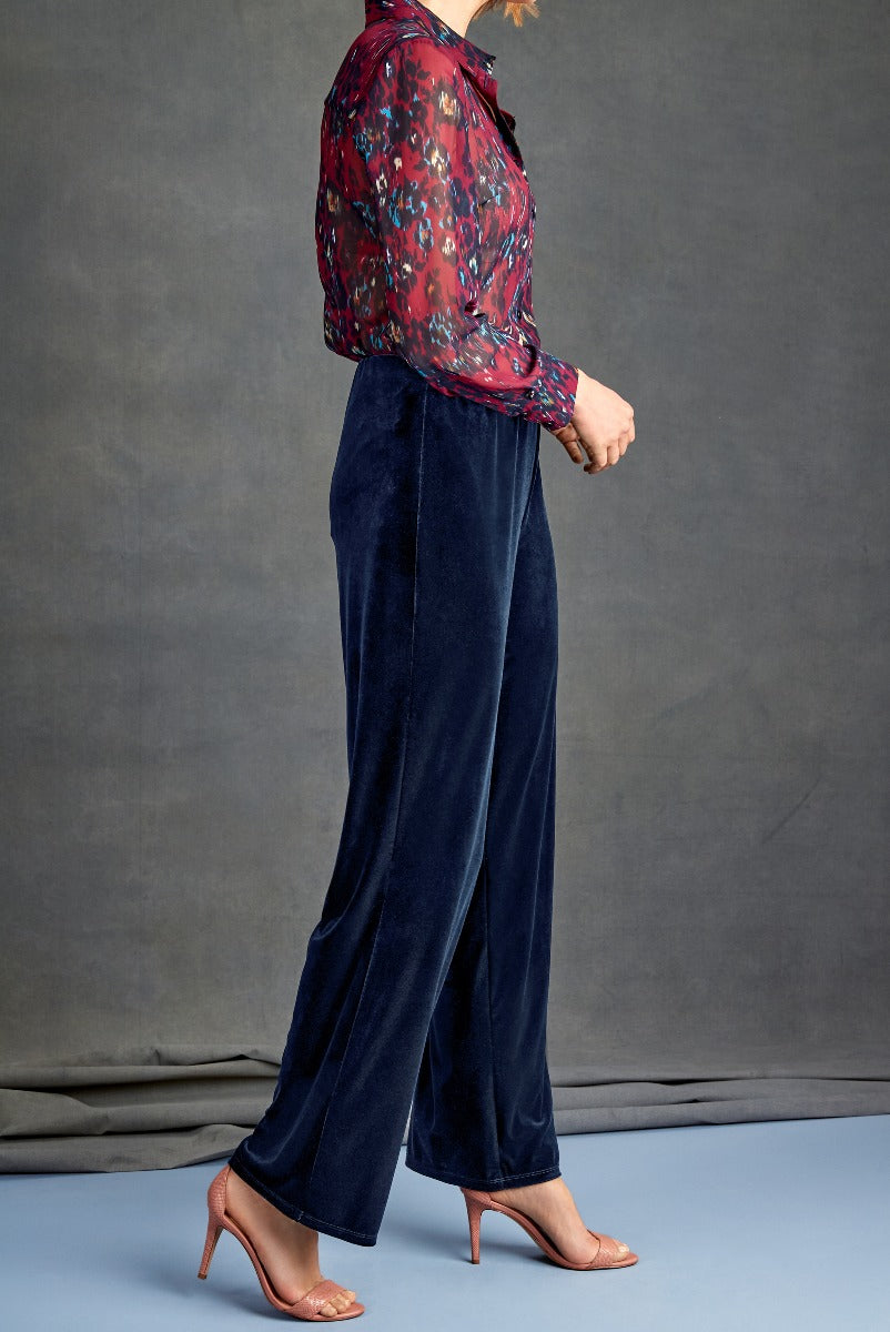 Lily Ella Collection fashion model wearing navy blue velvet trousers and a red floral blouse paired with tan strappy heels, stylish women's apparel, modern chic outfit.