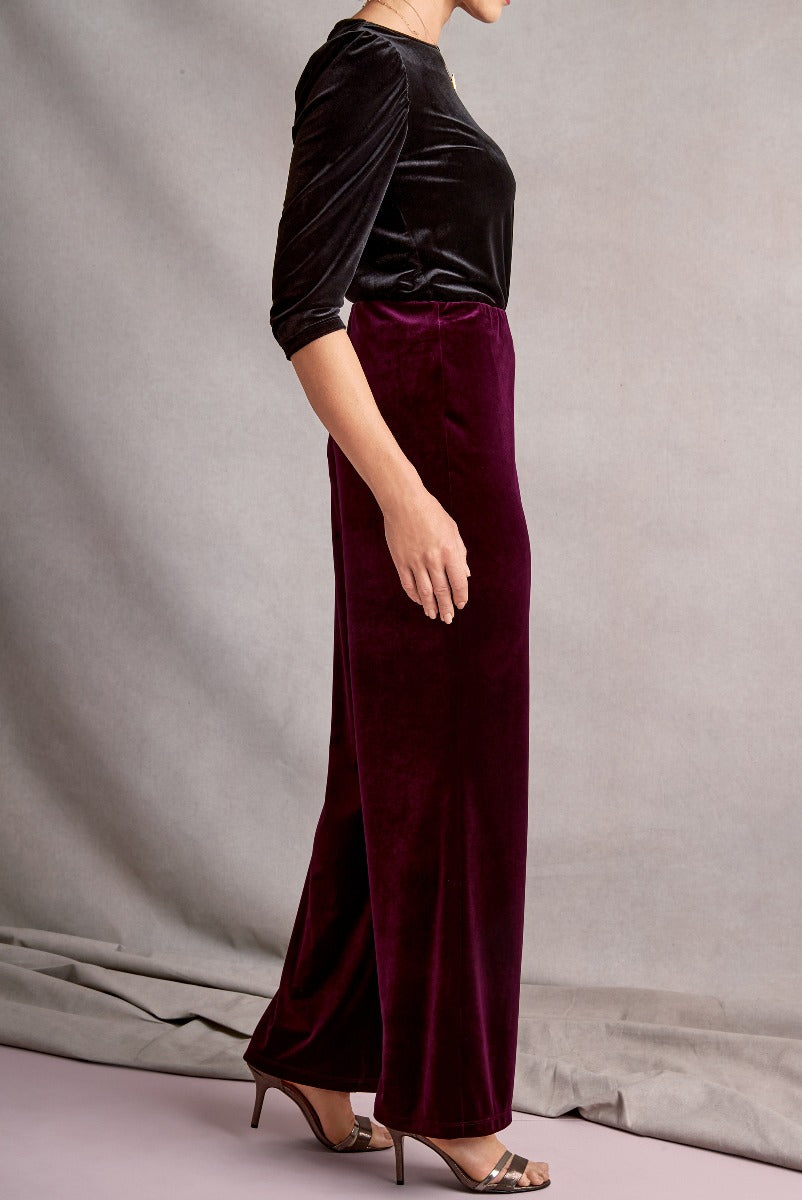 Lily Ella Collection elegant burgundy velvet trousers with black satin blouse, women's sophisticated evening wear, side view showing fabric texture and fit