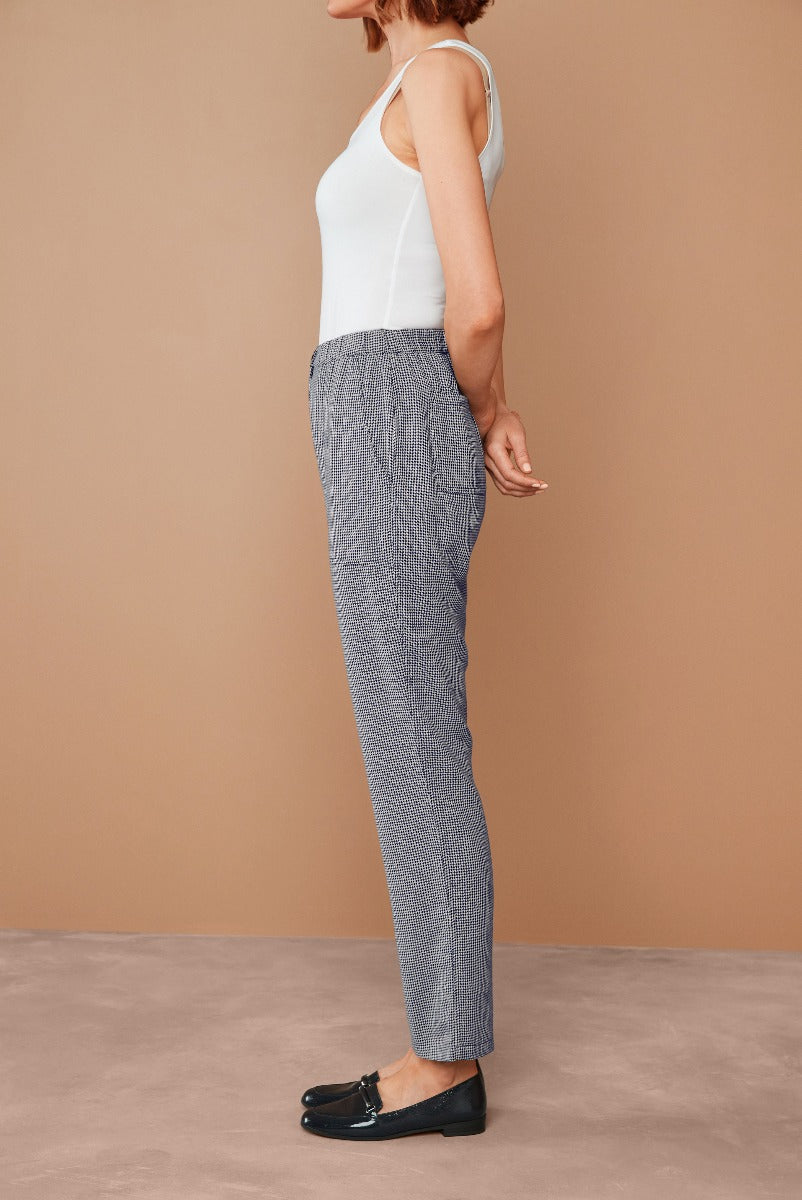 Lily Ella Collection women's fashion, model wearing black and white patterned trousers, paired with a white sleeveless top, showcasing casual style clothing, with beige background.