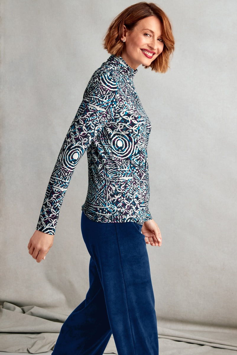 Lily Ella Collection stylish woman smiling in patterned turtleneck top and navy velvet trousers, contemporary chic fashion, elegant outfit idea