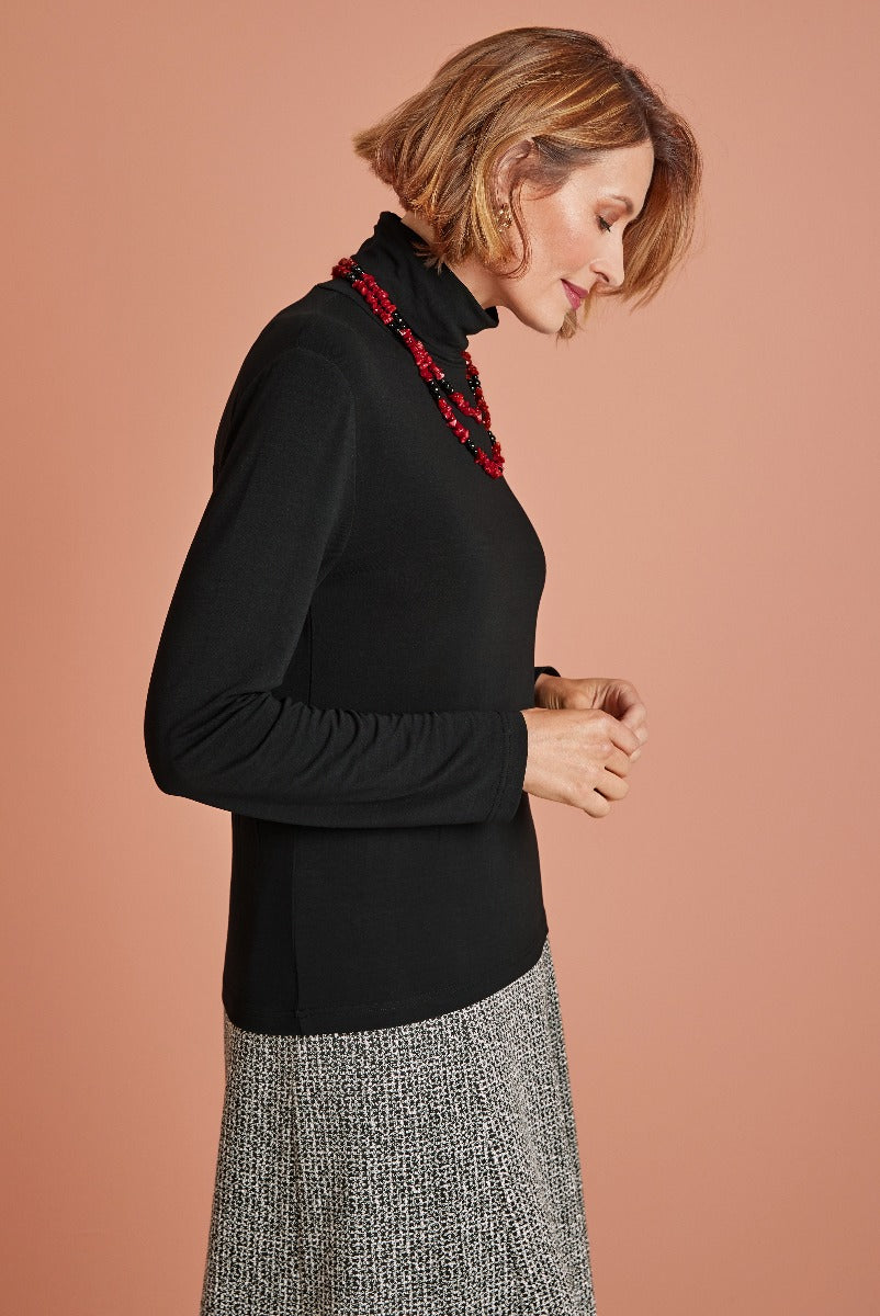 Lily Ella Collection elegant black turtleneck sweater with ruched sleeves and decorative red bead neckline on a model, paired with a patterned skirt, sophisticated women's fashion.