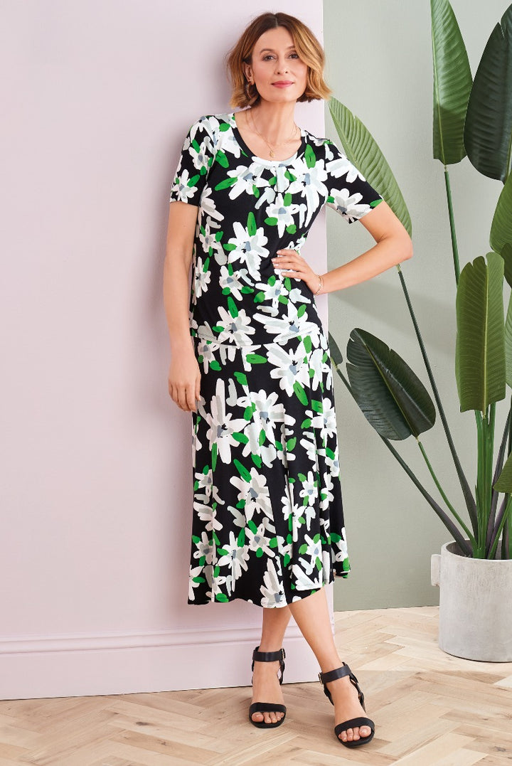 Lily Ella Collection black and white floral dress with short sleeves and knee-length hem, stylish women's A-line summer dress, model showcasing elegant fashion against indoor plant backdrop.