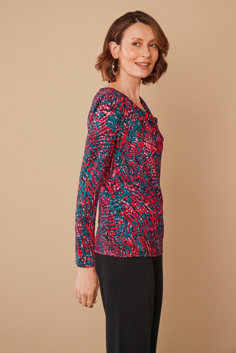 Lily Ella Collection abstract print top in vibrant pink and blue, stylish long sleeves, comfortable fit for mature women, paired with classic black trousers, elegant casual wear, ideal for daytime and work.