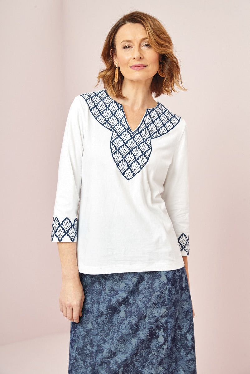 Lily Ella Collection white tunic with blue embroidered neckline and sleeve details paired with navy blue patterned skirt, stylish mature women's fashion, elegant daywear look
