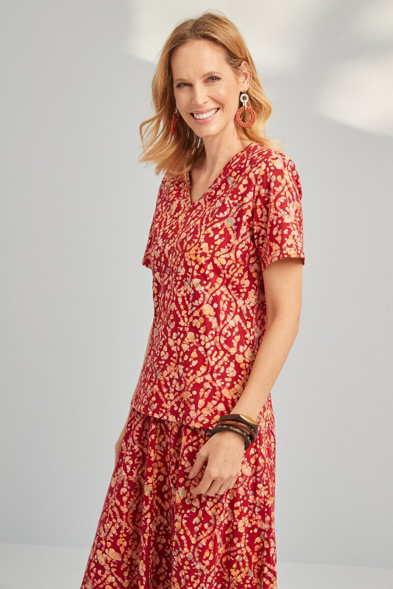Lily Ella Collection red floral-patterned summer dress with V-neck and short sleeves, styled with coordinating accessories on smiling female model.