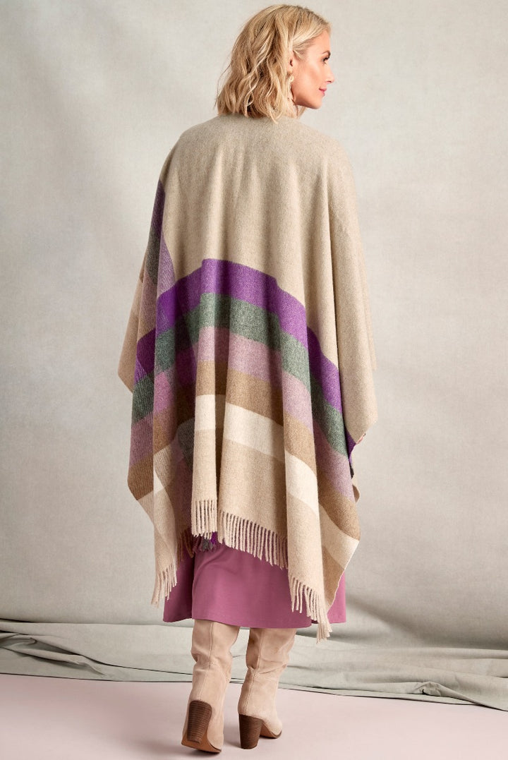 Lily Ella Collection beige checkered poncho with fringe detailing, paired with pink dress and nude knee-high boots, stylish women's autumn fashion.